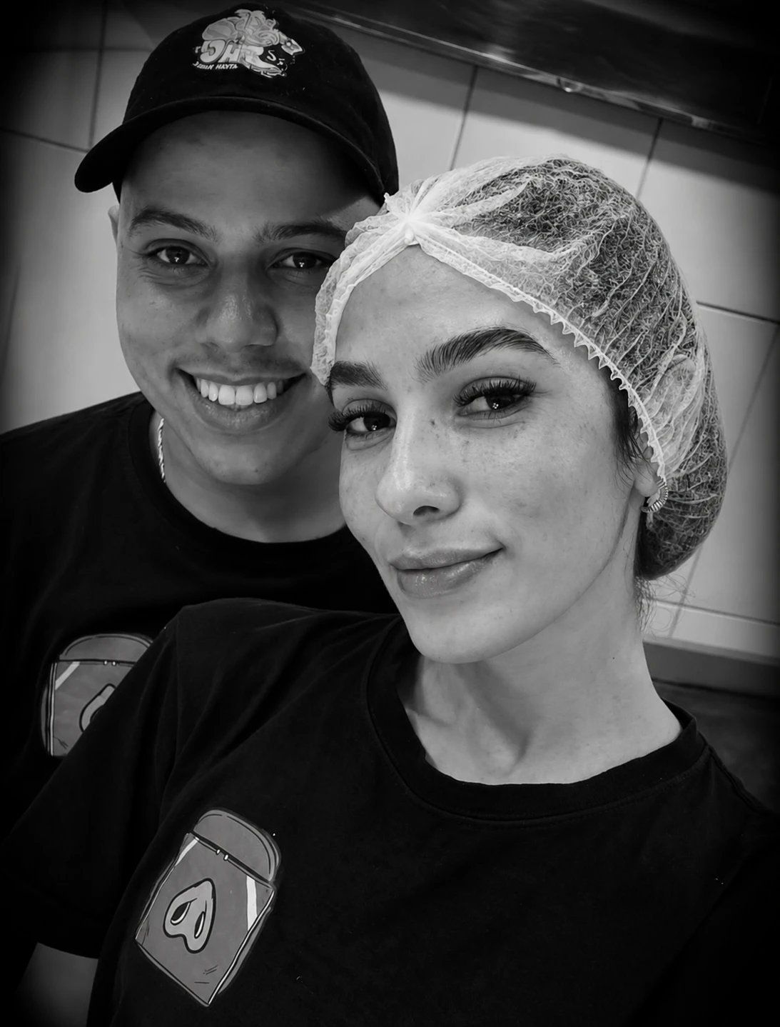 Hiago Carmo e Dienne Braga sorrindo juntos na cozinha do HC, ela de touca