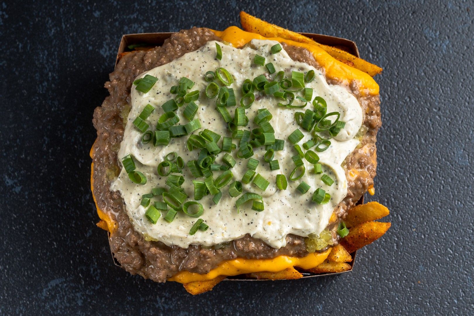 Fritas Especial do HC: Batata frita com carne smashada, cheddar, picles, maionese da casa e cheiro-verde por cima.